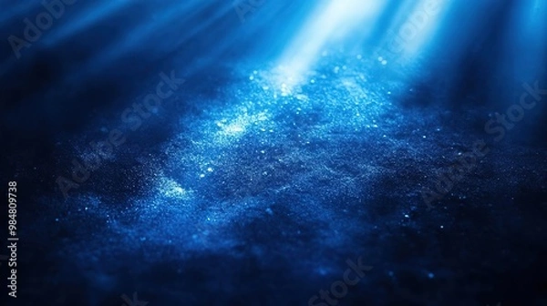 Obraz A serene underwater scene illuminated by beams of light, showcasing the beauty of deep blue water and floating particles.