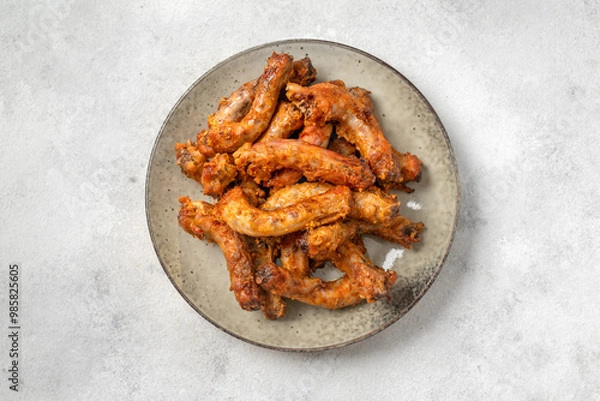 Obraz Baked chicken necks in a ceramic plate on a light culinary background top view