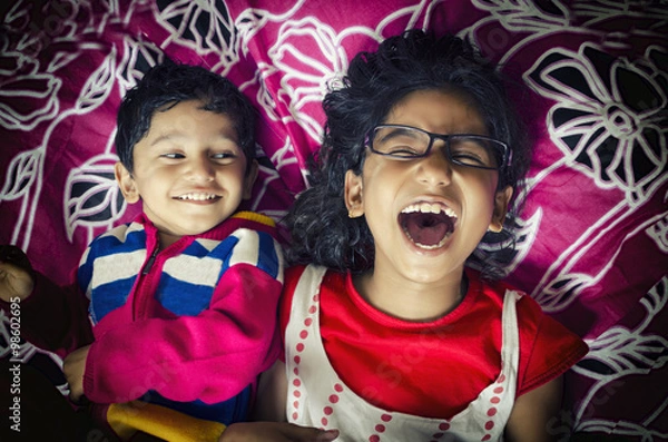 Obraz laughing happy sibling children playing having fun on bed
