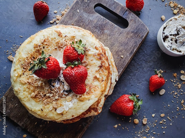 Fototapeta Pancakes with cream and strawberries on wooden board and dark rustic background