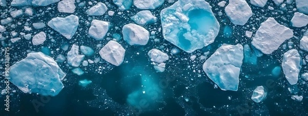 Fototapeta An aerial view of an iceberg floating in the water, showcasing its massive size and intricate details. The cold blue tones of the ice contrast with the dark ocean waters.