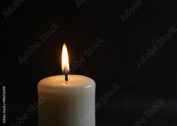 Fototapeta a white candle on a black background