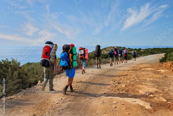 Obraz group of tourists with large backpacks are on road sea