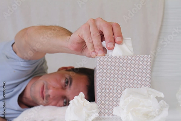 Fototapeta Man caught cold , flue, running nose, selective  focus on  tissue box. Healthcare and medical concept