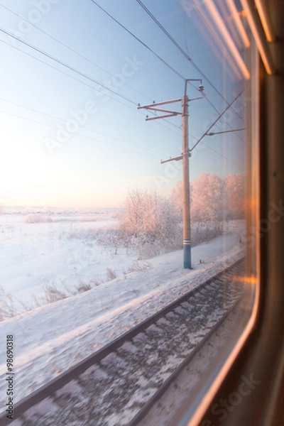 Obraz frozen pink sunrise in winter forest through the window of the train