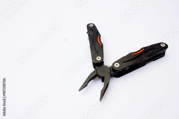 Fototapeta A black multifunctional pliers. It features several additional tools such as a knife, small saw, folding knife, etc.