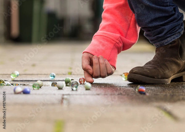 Obraz Child playing with marbles on yhe sidewalk.
old-fashioned toys still in use today.
