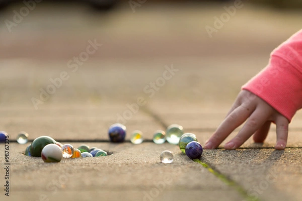 Obraz Child playing with marbles on yhe sidewalk.
old-fashioned toys still in use today.