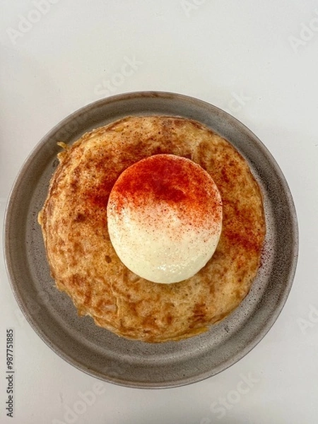Obraz Spanish frittata, common dish in Spain made with eggs and potatoes.  Mayonnaise and paprika topping.  Served on a plate, then on a white background.  View from the top. 