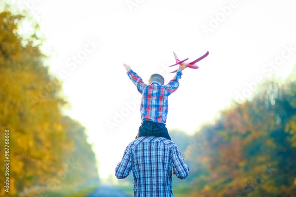 Fototapeta A Happy parent walks along the road with a child and an airplane in the park on nature travel