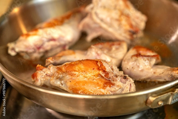 Fototapeta Portions of rabbit meat are fried in a frying pan closeup