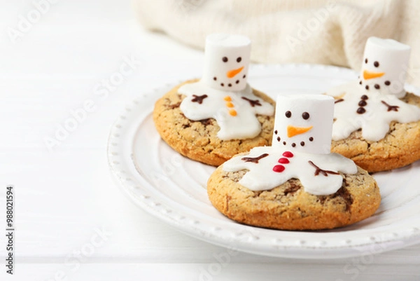 Obraz Delicious cookies with snowmen made of marshmallows on white table, closeup. Space for text