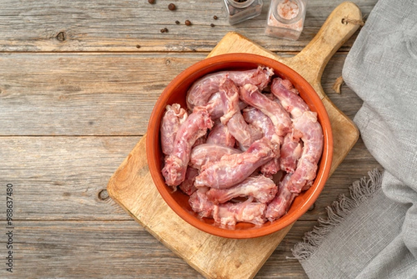 Obraz Raw chicken necks in a bowl on a gray wooden culinary background. Top view with a copyspace