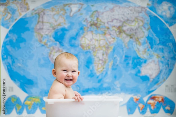 Fototapeta Baby sitting in a box, on a background map