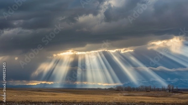 Fototapeta Sunlight through storm clouds, creating dramatic beams across the landscape
