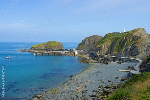 Fototapeta Elevated view of the landing bay of the Lundy Island and  Lundy South Lighthouse in the Bristol Channel in tranquil day
