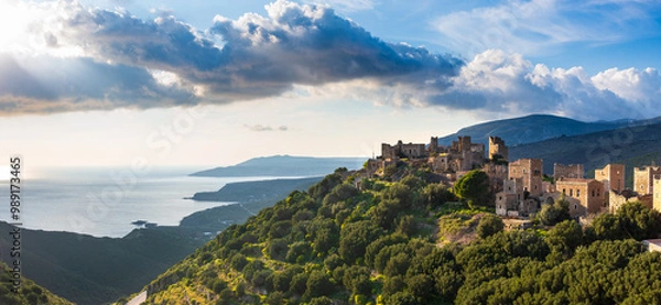 Fototapeta sunset illuminating the medieval village of vathia on the mani peninsula, greece. The sun setting over the mediterranean sea, illuminating the stone houses of hilltop medieval village