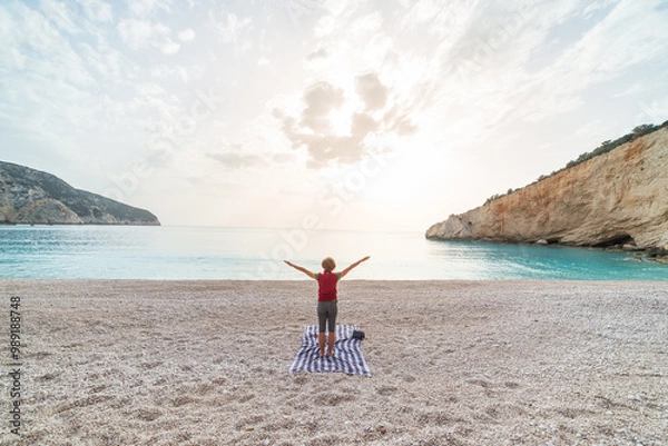 Fototapeta Woman performing yoga exercises on a beautiful empty beach in Greece. Dramatic coastline scenic bay rocky cliffs in the Ionian islands.