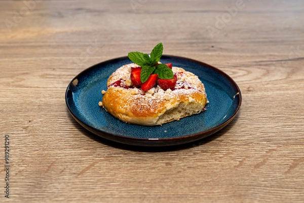 Obraz Handmade yeast cake with strawberries and pudding, lying on a blue plate.