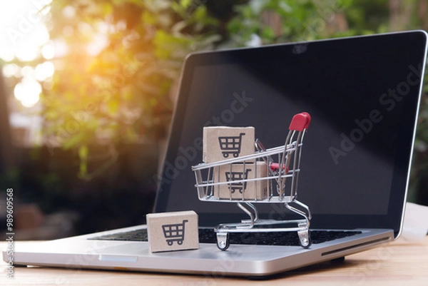 Fototapeta Shopping online. cardboard box with a shopping cart logo in a trolley on laptop keyboard. Shopping service on The online web. offers home delivery