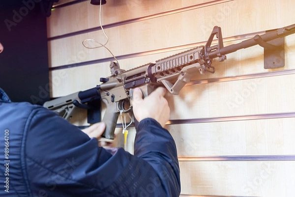 Obraz A man with an automatic rifle in a gun store.