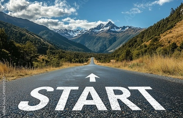 Fototapeta Photo of an empty road with the word "Start" written on it, leading to mountains and forests in the background. The arrow pointing towards a bright future symbolizes the beginning of a new journey or 