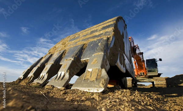 Fototapeta Large orange backhoe parked at a construction site