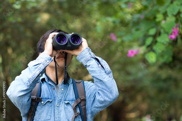 Fototapeta Young Man watching though binoculars