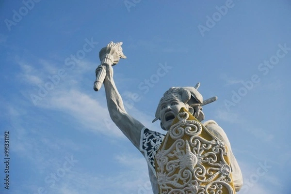Fototapeta a welcome statue in the form of a Dayak man from Balikpapan city with isolated blue sky