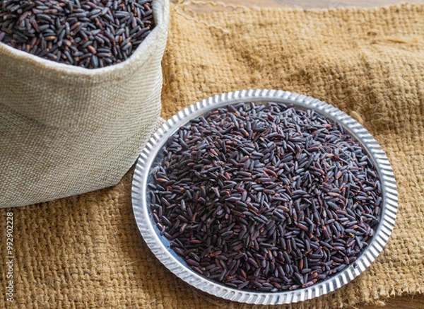 Fototapeta Riceberry is a dark purple rice with a fragrant aroma and high antioxidant content. It is a cross between black jasmine rice and jasmine rice. Riceberry rice grains on a plate.