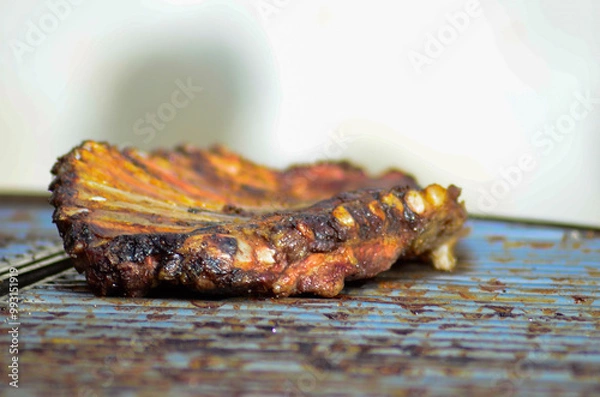 Fototapeta Ribs roasted over a slow fire on a metal grill