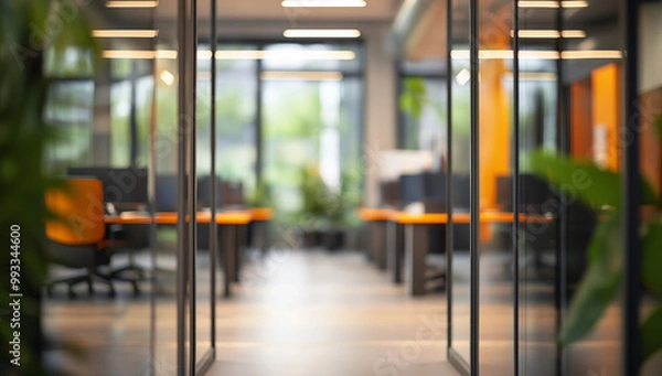 Fototapeta Open glass doors to a blurry office space with desks, computers, and plants