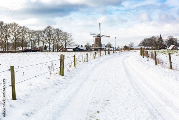 Fototapeta Dutch winter landscape with snowy road and windmill in the background, Garderen, The Netherlands