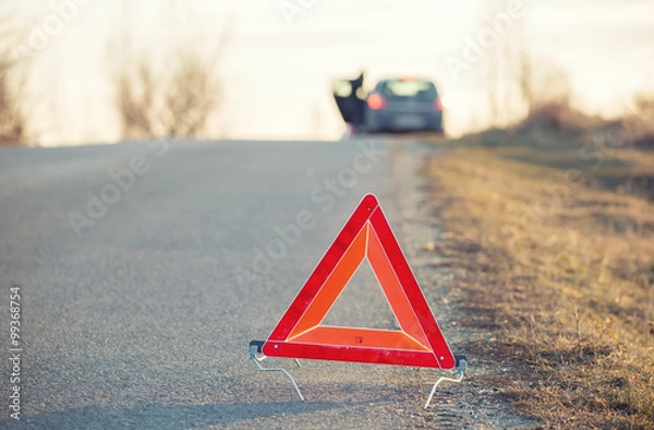 Fototapeta Red warning triangle on a road with a failure car