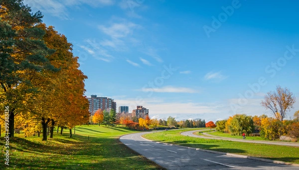 Fototapeta Traffic along Ottawa riverside parkway - runners on winding paved pedestrian path.    Panoramic view following Ottawa River.  Apartments & condos along parkway.
