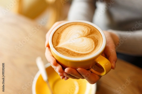 Fototapeta lady's hands holding cup with sth heart-shaped