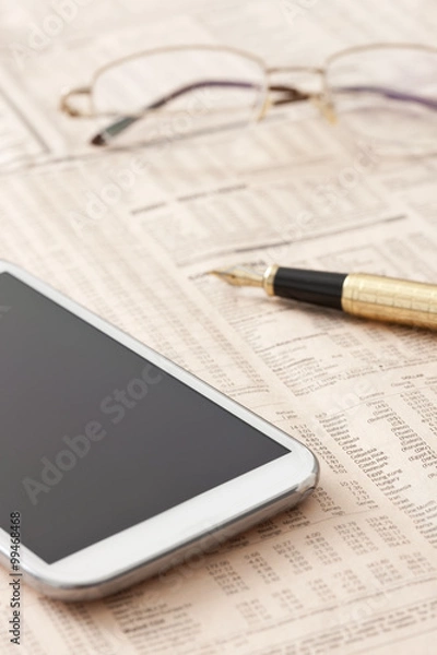 Fototapeta Financial newspaper and mobile phone on desk