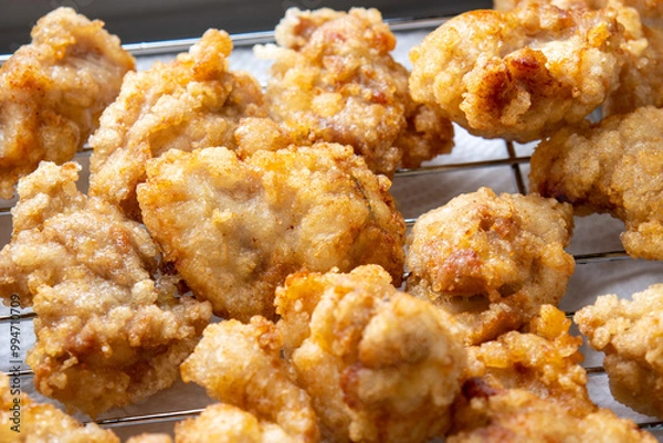 Obraz 揚げバットに上げられた、揚げたての鶏もも肉の唐揚げ。
