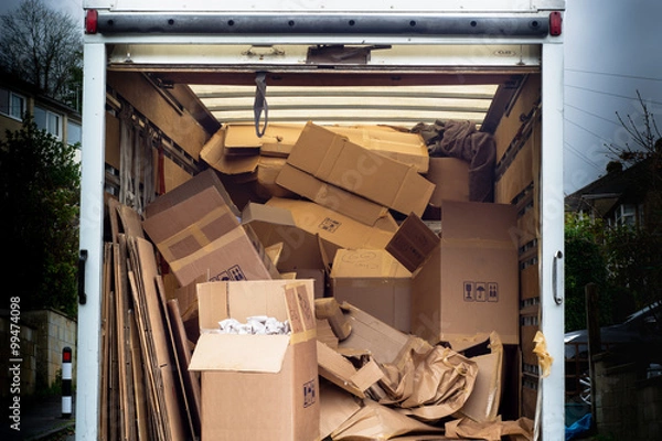 Fototapeta Removal van with untidy boxes dumped inside. A removal lorry is filled with carelessly thrown boxes
