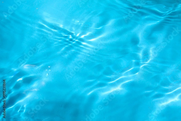 Fototapeta Blue water with ripples on the surface. Defocus blurred transparent blue colored clear calm water surface texture with splashes and bubbles. Water waves with shining pattern texture background.