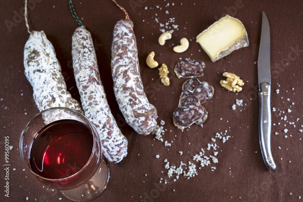 Obraz Aperitif with red wine, saucisson, cheese and nuts