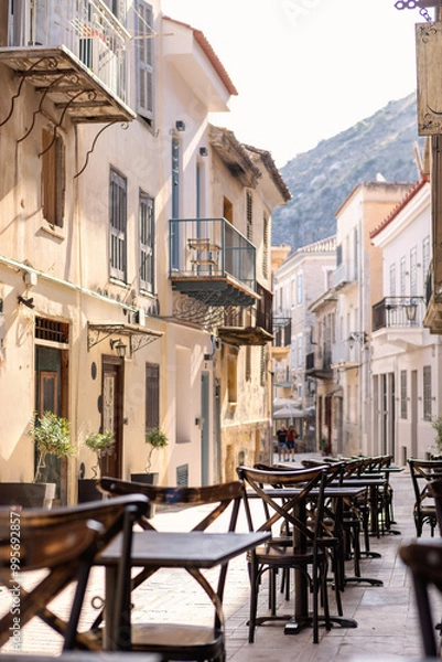 Obraz The lively café at Alley Nafplio invites visitors to relax and savor the warmth of the sun, enveloped by beautiful old architecture and vibrant street life.