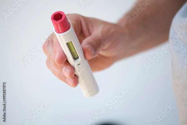 Fototapeta Detail of An anonymous man with pen injector in his hand for a biological or insulin type medical treatment. It is a modern injectable healthcare drug such as Adalimumab, Etanercept or epinephrine
