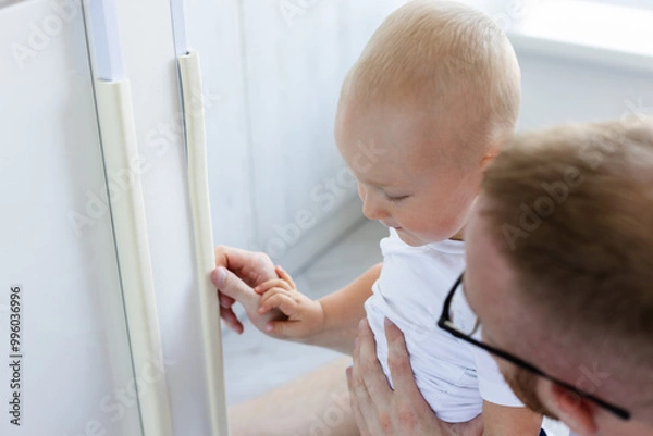 Fototapeta Father explain to his child that he must be careful with dangerous corners of walls and furnitures at home.