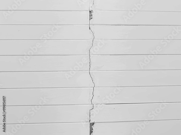 Obraz Abstract background close-up of crack white wooden panelling wall, highlighting structural issues. a glossy white panels contrasts with the dark line of the crack, damage, repair, maintenance concept.