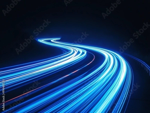 Fototapeta Long exposure photograph of blue neon light trails on a curved path against a dark background, evoking a sense of motion and speed.