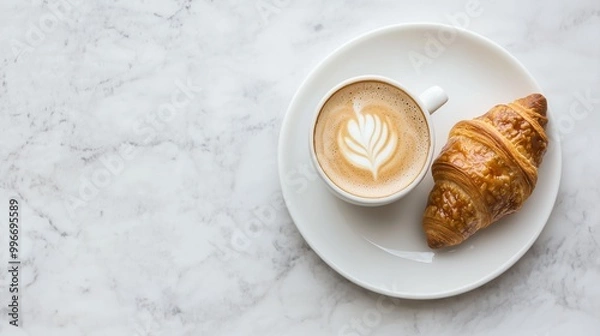 Fototapeta A warm cup of coffee paired with a flaky croissant on a marble surface, perfect for a cozy breakfast or brunch setting.