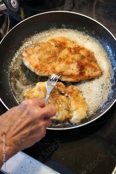 Obraz Close-up of an elderly woman's hand frying cutlets in a pan
