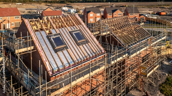 Fototapeta Aerial view of a roof under construction with attic room and skylight window on a new build housing development