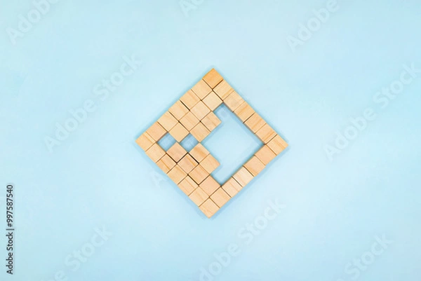 Fototapeta 水色の背景で右向きの矢印の形を残した四角く並べたウッドキューブの正面